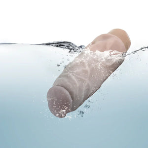 Realistic flesh-colored sex toy splashing into clear water with bubbles