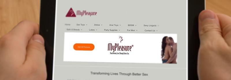 Hands holding tablet displaying MyPleasure adult products online store homepage