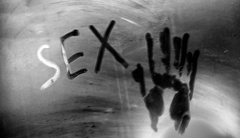 Word 'SEX' and a handprint drawn on a fogged-up glass shower door in black and white