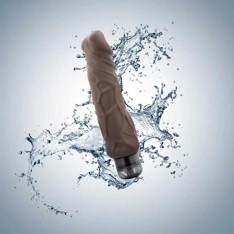 Brown textured vibrator with silver base splashing through water on light background